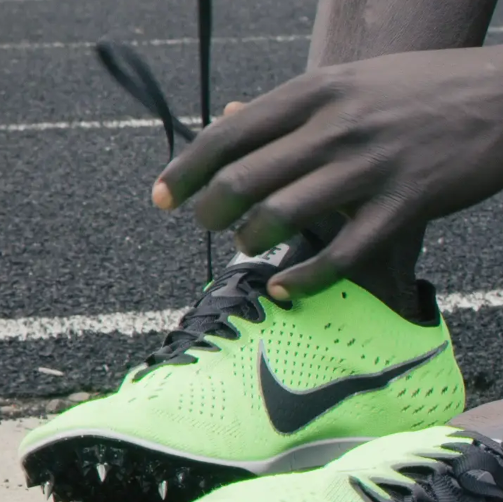 refugee man ties his shoes on a running track
